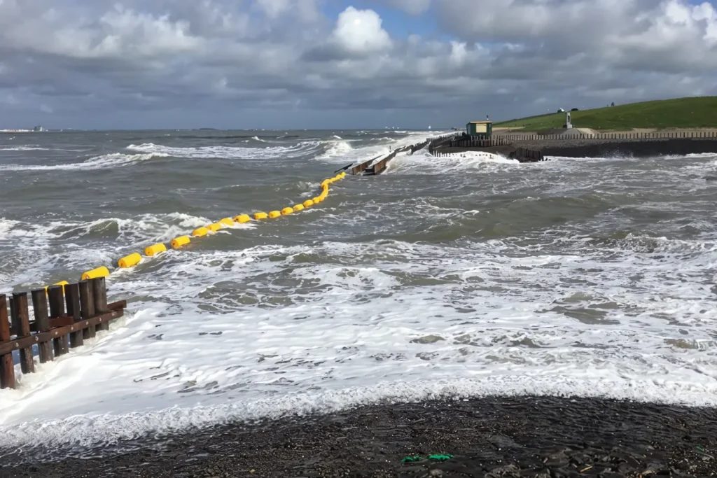 Heavy-duty HDPE boom floating in rough sea conditions, providing a durable barrier against waves and protecting the shoreline.