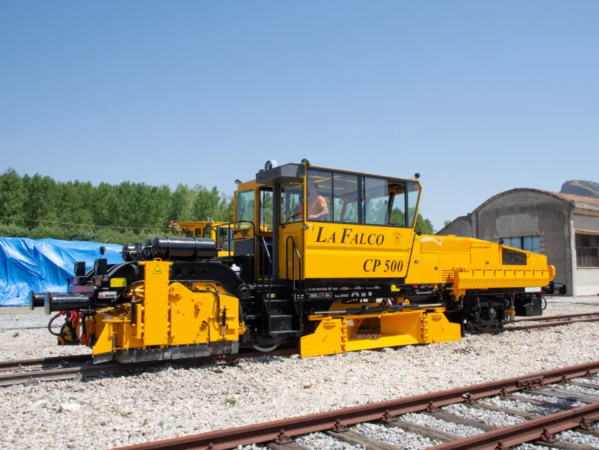 Yellow ballast regulator equipment on railway tracks for ballast maintenance and track bed shaping.