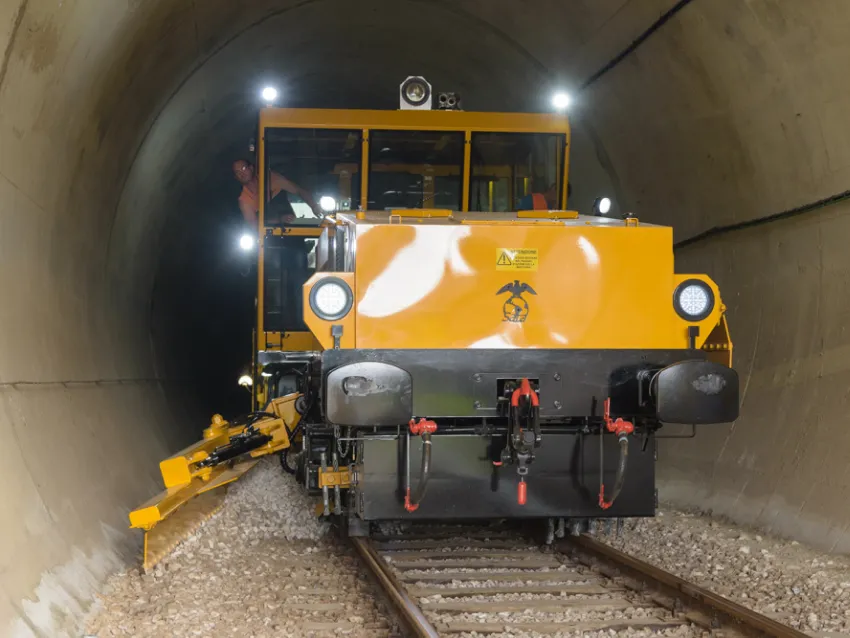 Ballast regulator machine working inside a railway tunnel for ballast maintenance and track profiling.