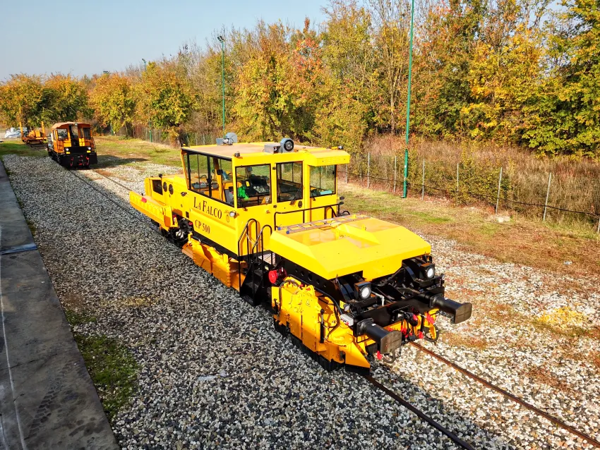 Ballast regulator machine working on railway tracks beside a station platform