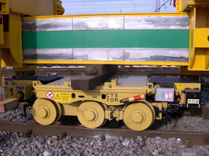 Motorized trolley carrying heavy rail equipment on railway tracks