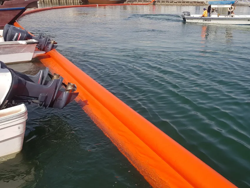 Inflatable oil boom beside boats