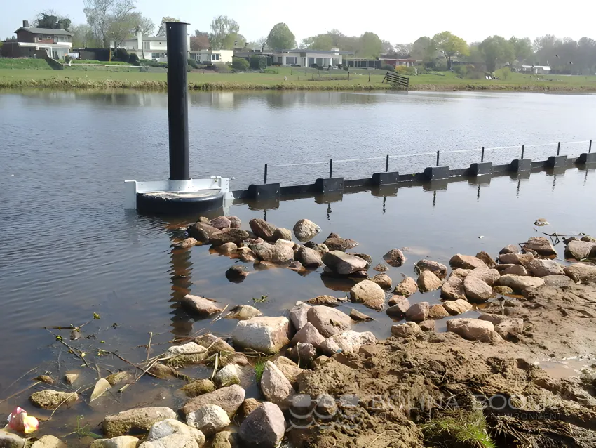 Floating debris barrier near a riverbank