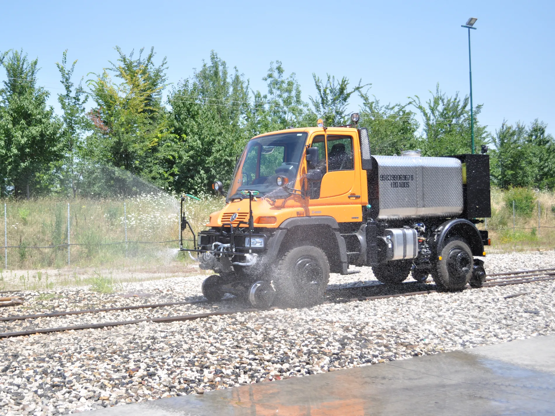 Hi rail truck operating on railway tracks for rail maintenance and track cleaning.