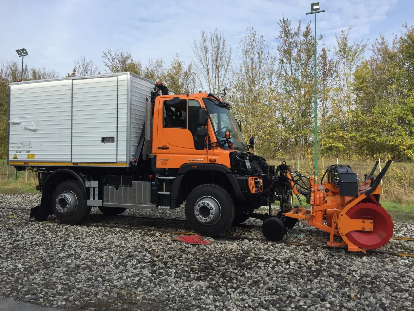 Hi rail truck on railway tracks with front-mounted maintenance equipment for rail service work.