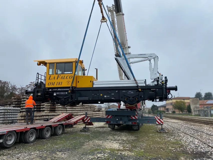 Switcher locomotive being lifted by crane for railway shunting equipment deployment.