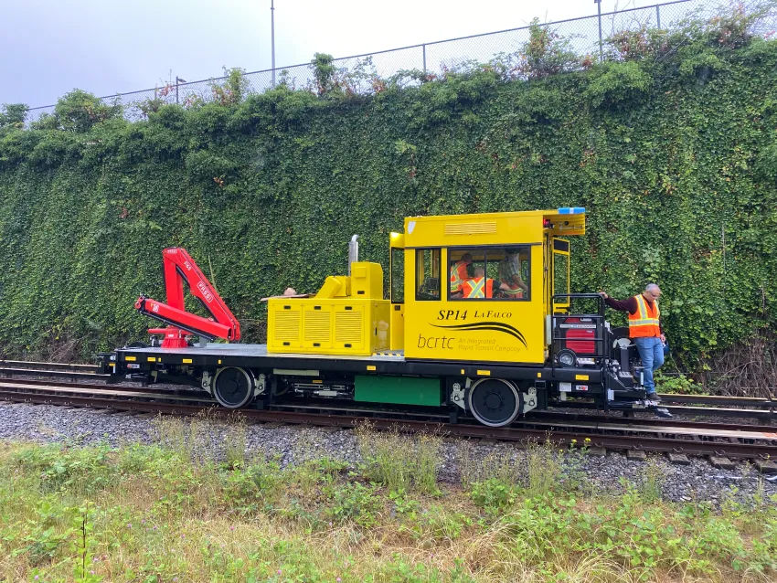Rail shunter with crane attachment on railway tracks for maintenance and industrial switching operations.