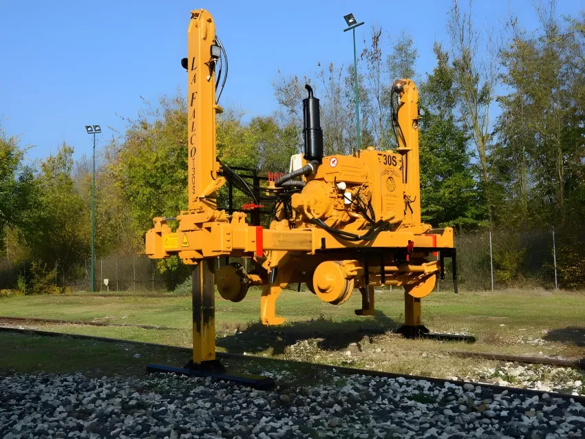 Track laying machine positioned on railway tracks for rail installation.